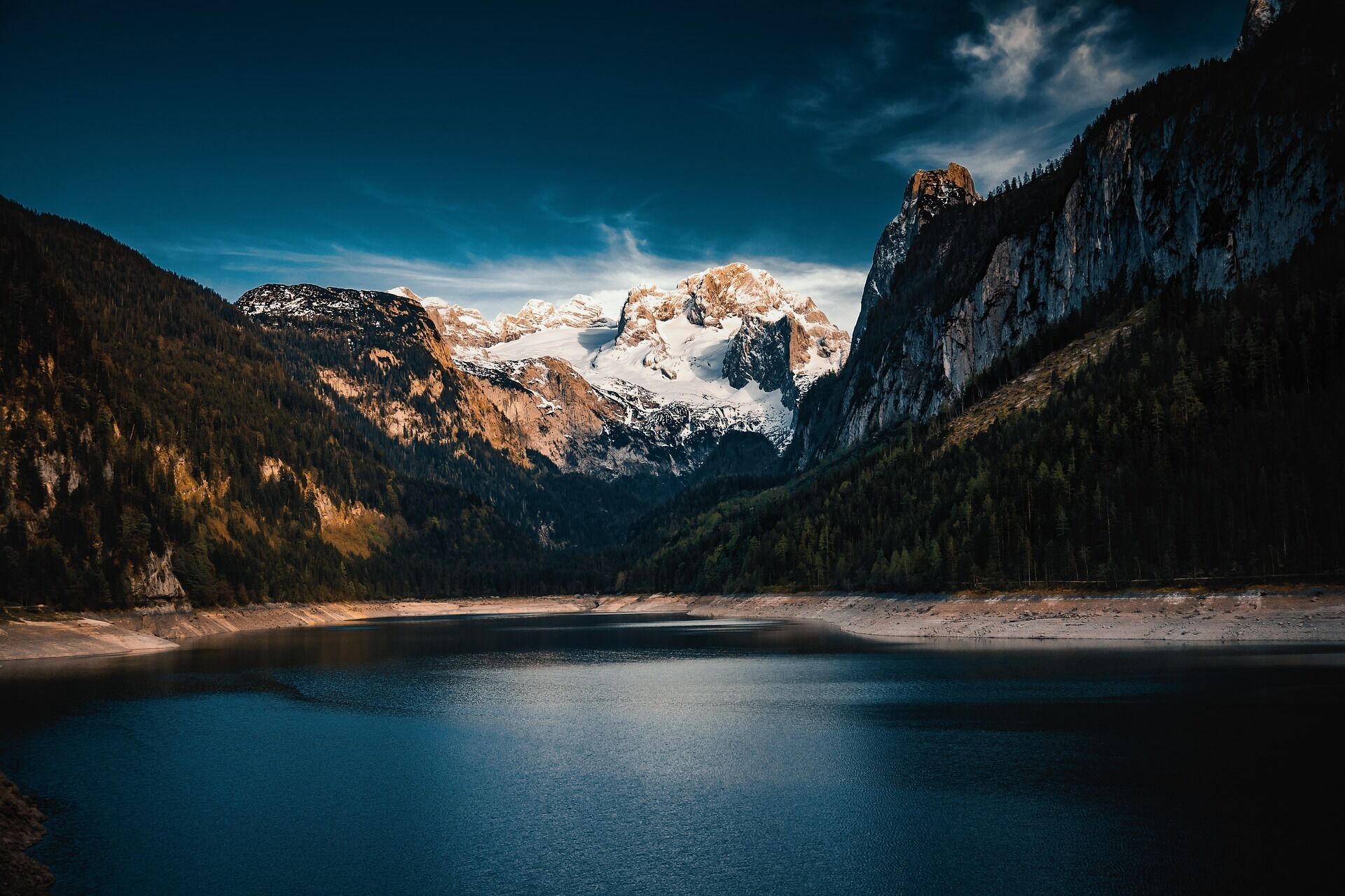 Un lago sereno rodeado de montañas boscosas bajo un cielo despejado.