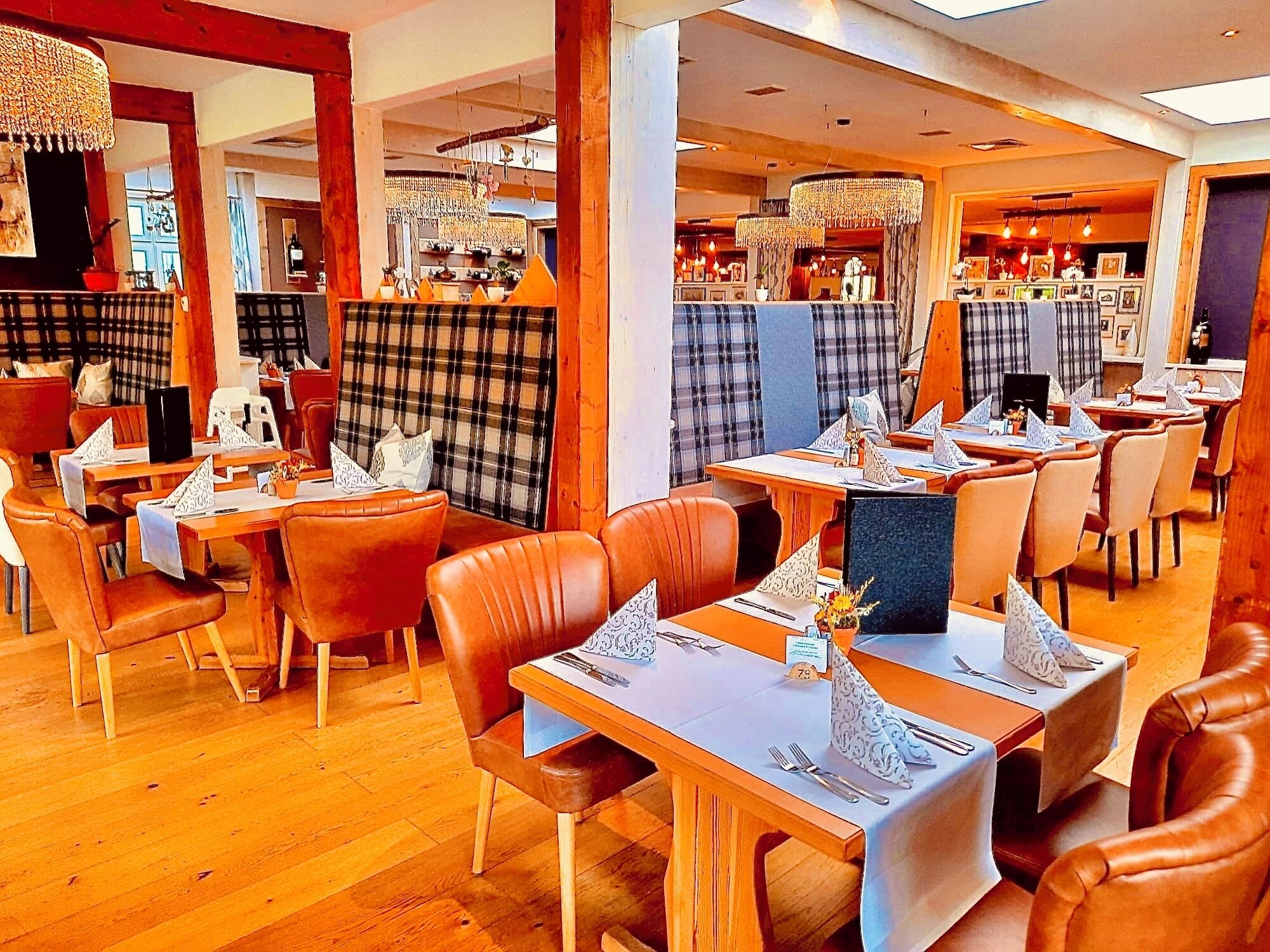 A restaurant with wooden tables and chairs, a bar area, and a view of the kitchen.