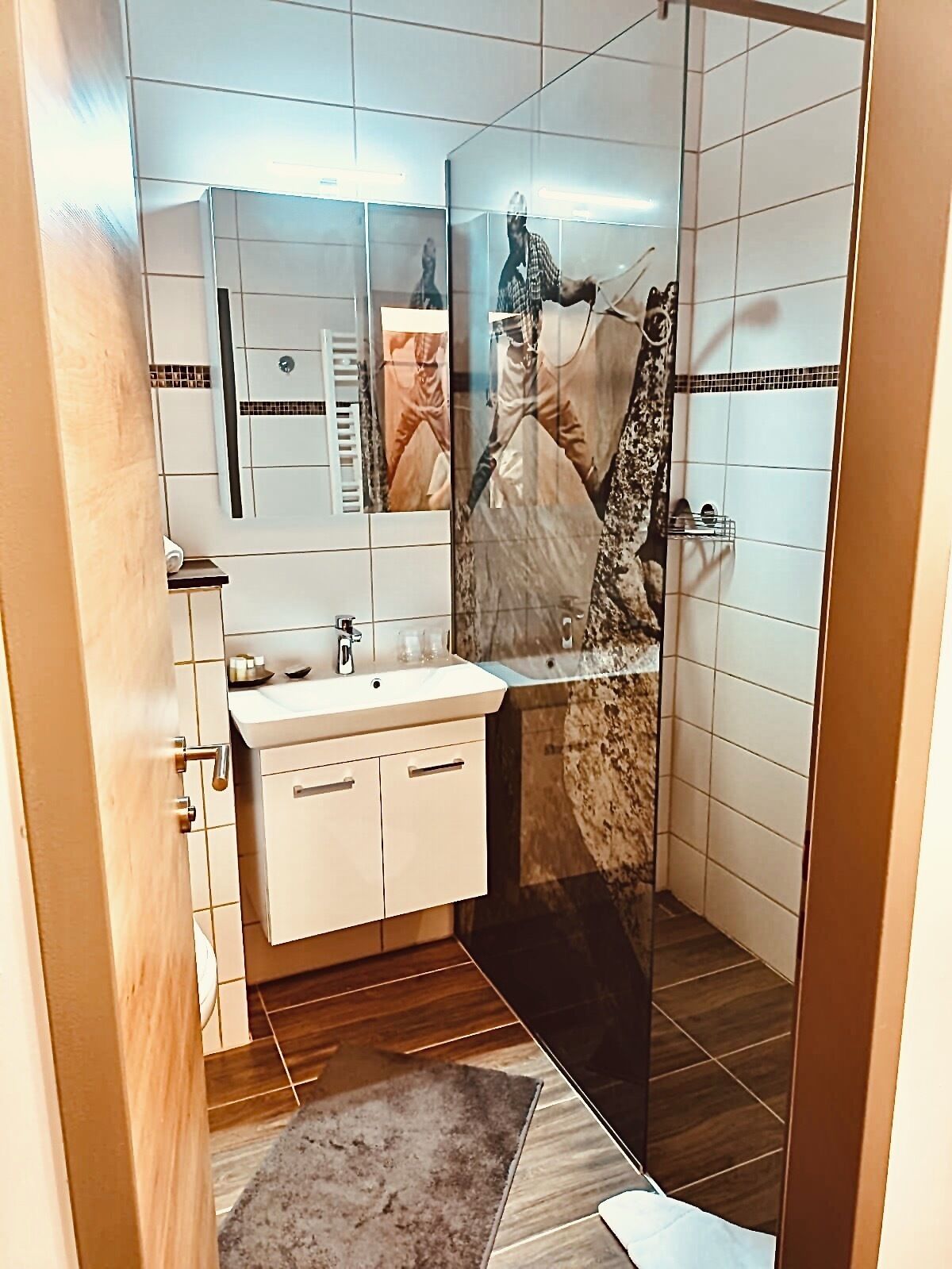 A bathroom with a sink, mirror, and shower area.