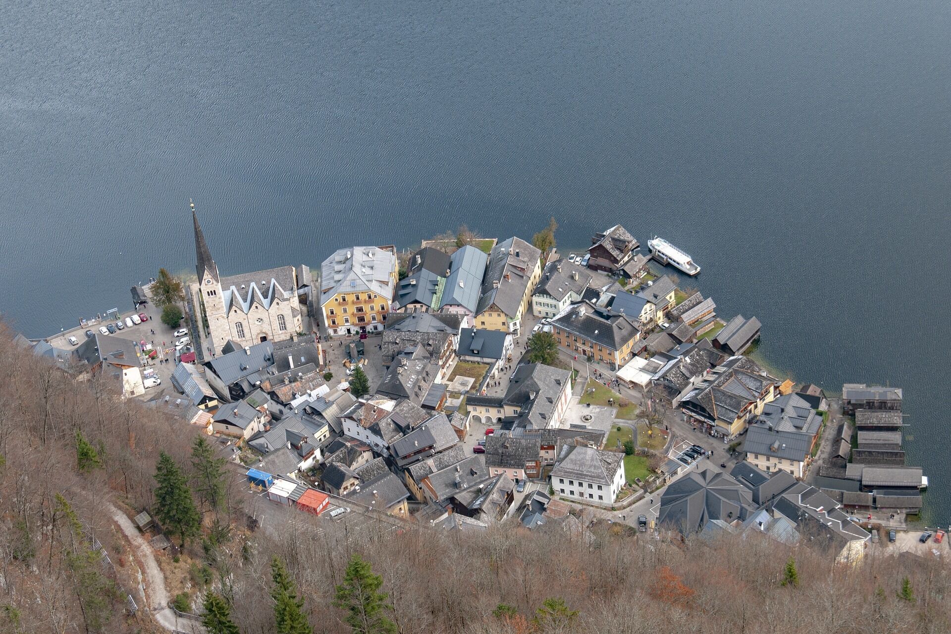 Un pueblo a orillas del lago con una mezcla de edificios residenciales y comerciales, incluyendo una iglesia con un campanario destacado.