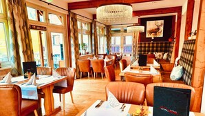 A restaurant with wooden interiors, leather seating, and a chandelier. - Apartment Hallstatt Dachstein Inn (Gosau)