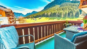 A balcony with wicker furniture, a wooden railing, and a view of a mountainous landscape. - Apartment Hallstatt Dachstein Inn (Gosau)