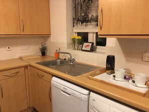 A kitchen with wooden cabinets, a sink, a dishwasher, and a coffee maker.