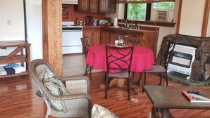 A cozy living room with a fireplace, wooden flooring, and a dining area with a red tablecloth. - Beautiful Loft Apartment Centrally Located for Recreation. (Union)