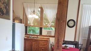 A wooden dining table with chairs, a kitchen area with wooden cabinets, a refrigerator, and a dining table with a red tablecloth. - Beautiful Loft Apartment Centrally Located for Recreation. (Union)