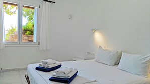 Een hotelkamer met een bed, een raam met gordijnen en een wandlamp.