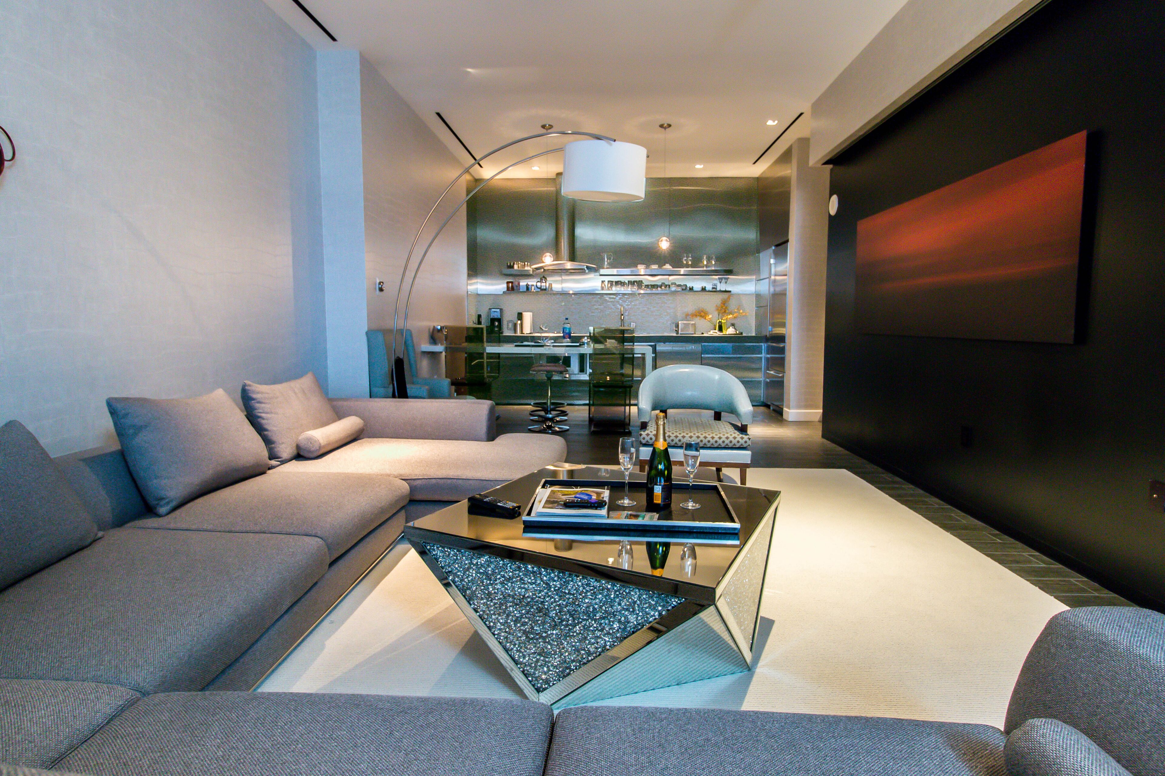 A modern living room with a sofa, coffee table, and a kitchen area in the background.