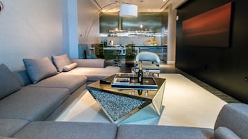 Un salon moderne avec un canapé, une table basse et un coin cuisine à l’arrière-plan.