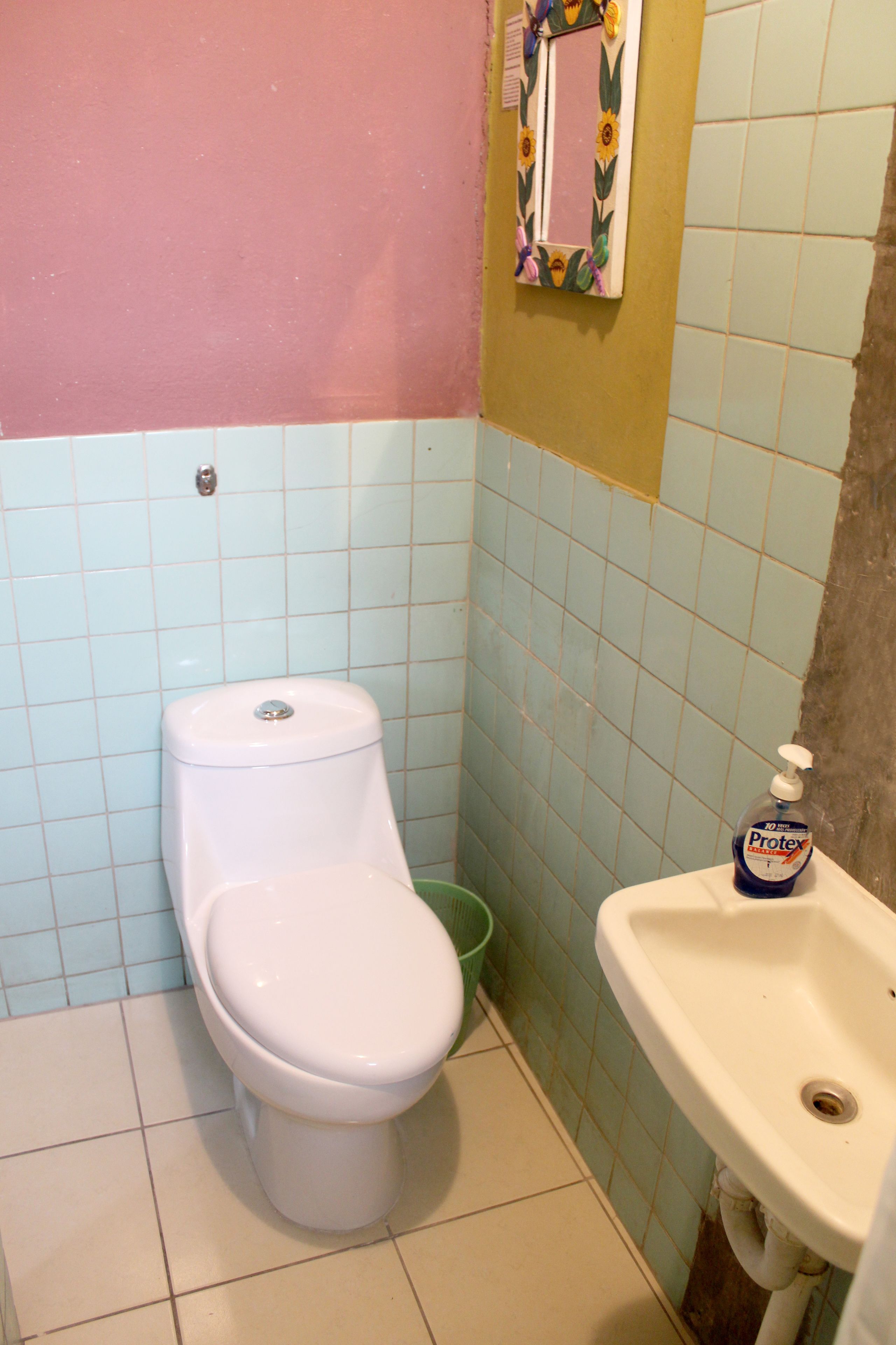 Un baño con inodoro, lavamanos y espejo decorado con un girasol.