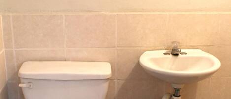 A bathroom with a toilet, sink, and blue trash bin.