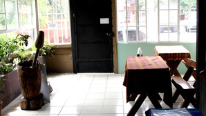 Una habitación con piso de baldosas, una puerta negra y dos mesas con manteles a cuadros.