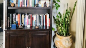 Une bibliothèque à plusieurs étagères remplie de livres, une plante en pot posée sur le dessus et un miroir accroché au mur.