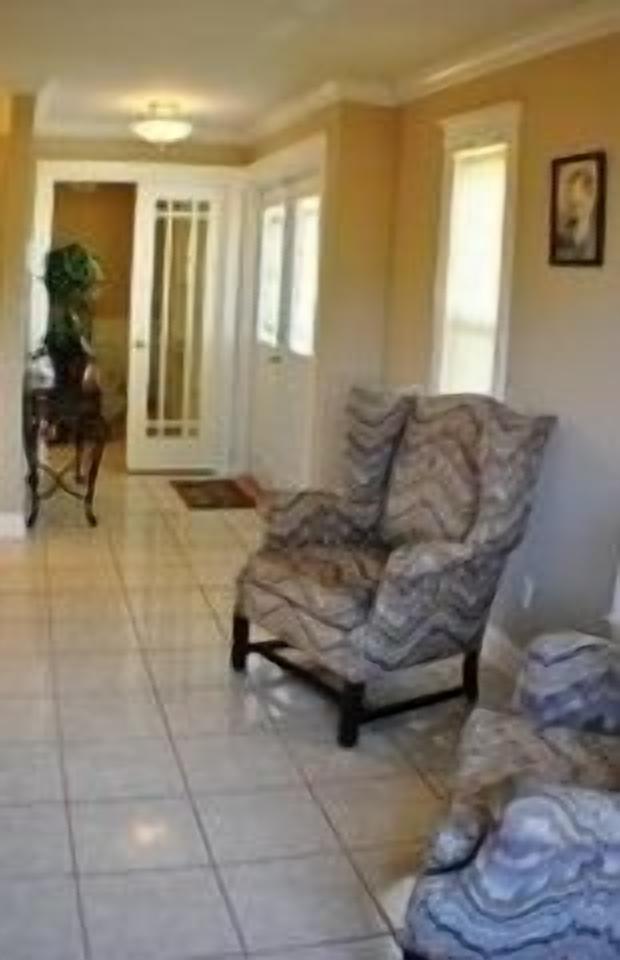 A living room with a patterned armchair, a dining area with a table and chairs, and a door leading to another room.