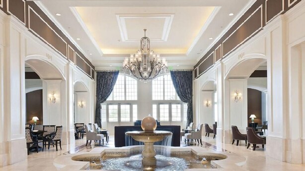 Un vestíbulo espacioso con una fuente central, elegantes candelabros y arquitectura clásica.