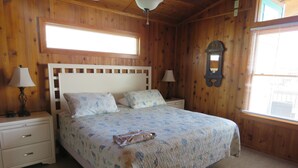 A wooden room with a bed, two nightstands, a ceiling fan, and a window. - Last Minute Special/ Elevator/Pool/Theater/Game Rm/Pool table/ping pong table (Nags Head)