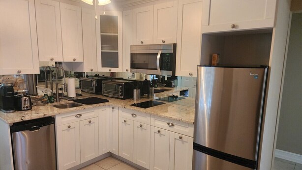A modern kitchen with white cabinets, stainless steel appliances, and a double sink. - Bayshore Inn & Docks Two Bedroom Unit 8 Overlooking the Pool (Naples)