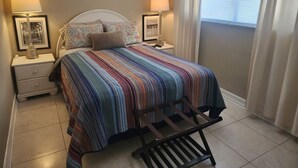 A bedroom with a striped bedspread, two bedside lamps, and framed pictures on the nightstands. - Bayshore Inn & Docks Two Bedroom Unit 8 Overlooking the Pool (Naples)