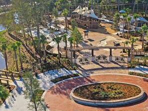 Stroll along the paved walkway surrounding a serene central water feature, surrounded by palm trees and a charming pavilion.