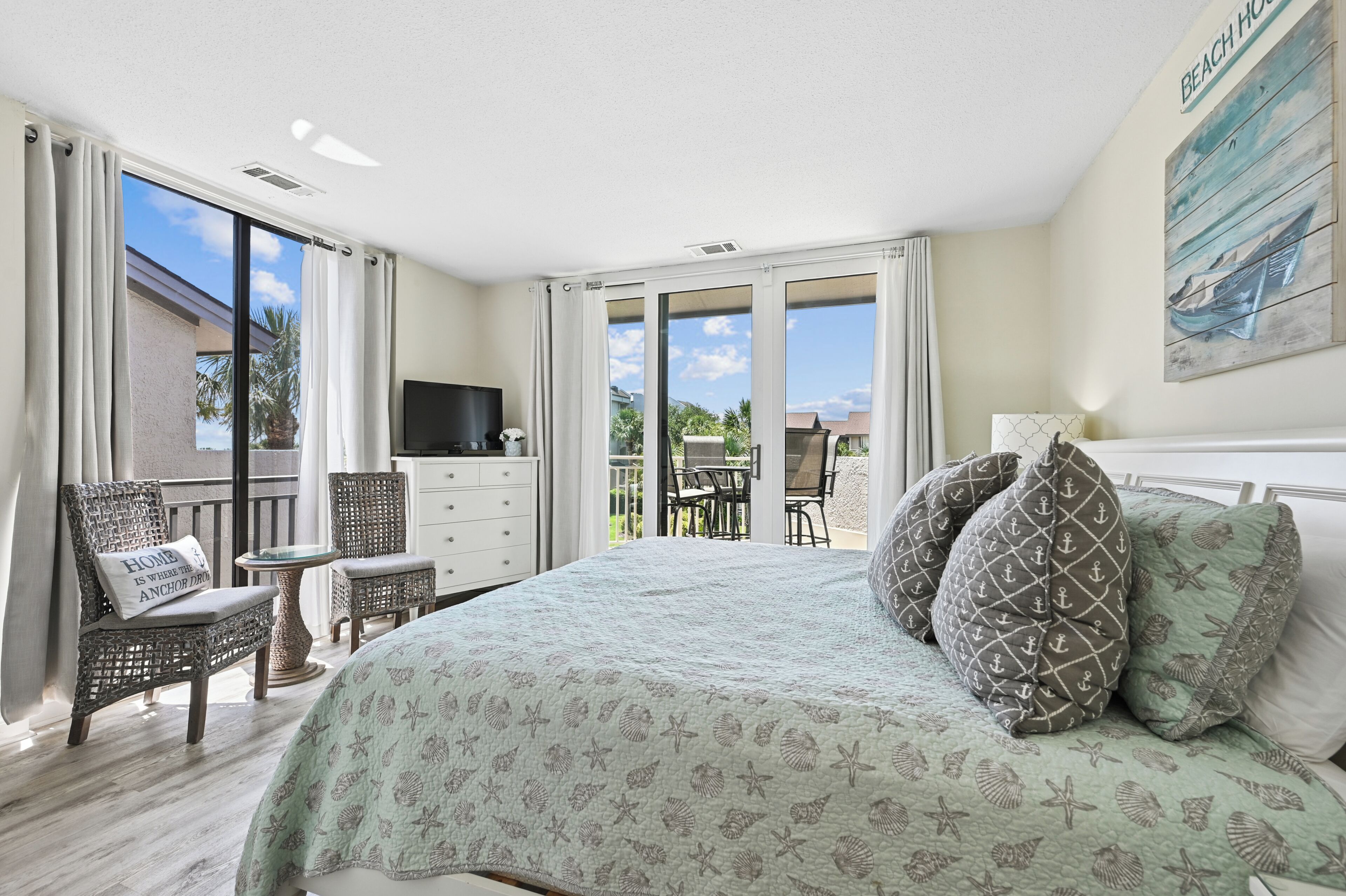 Ein Schlafzimmer mit einem großen Bett, einem Fernseher, einem Schreibtisch und einem Balkon mit Blick.