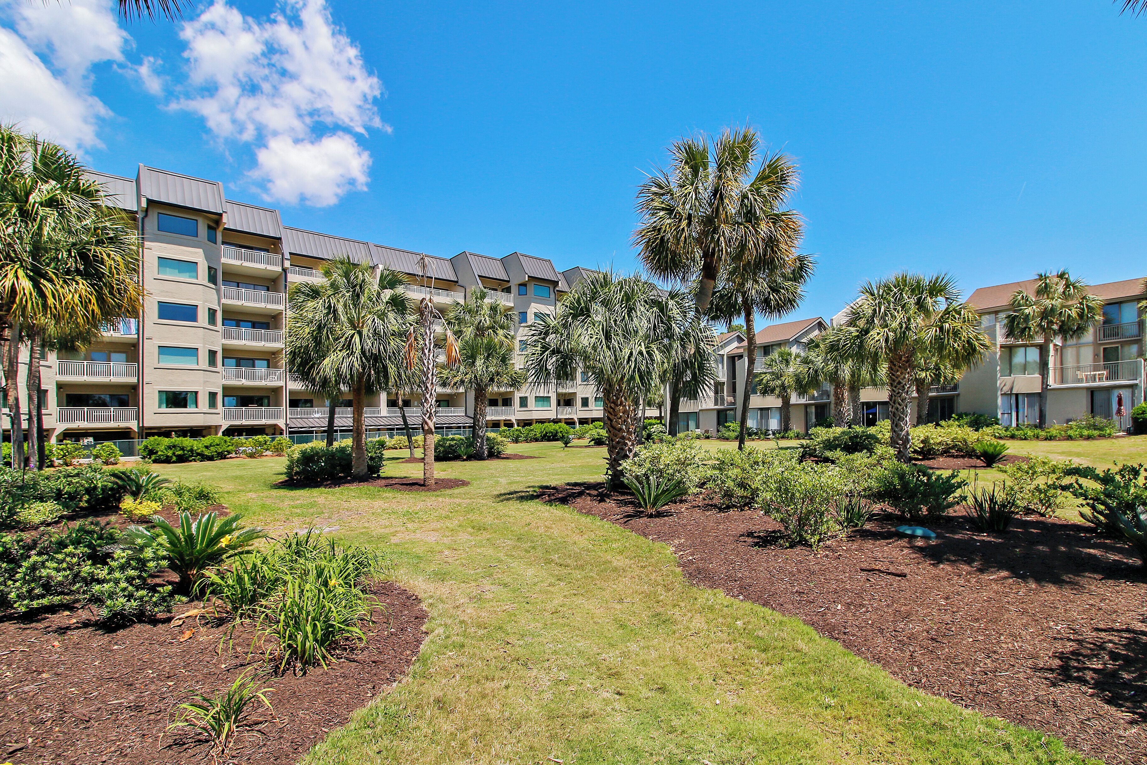 A hotel courtyard with multiple floors, palm trees, and well-maintained lawns.