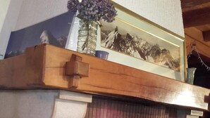 Une cheminée avec un manteau en bois, un tableau encadré au-dessus, et une lanterne blanche placée à côté du foyer.
