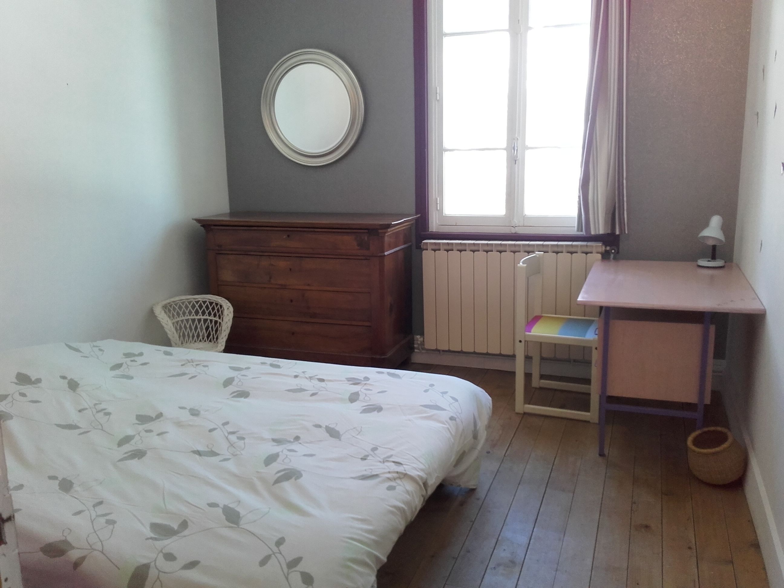 Un dormitorio con cama, cómoda, silla, escritorio y ventana con cortinas.
