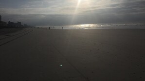 Een strand met een heldere lucht en de zon die schijnt.