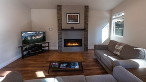 Ein Wohnzimmer mit Kamin, Fernseher und einer Couch.