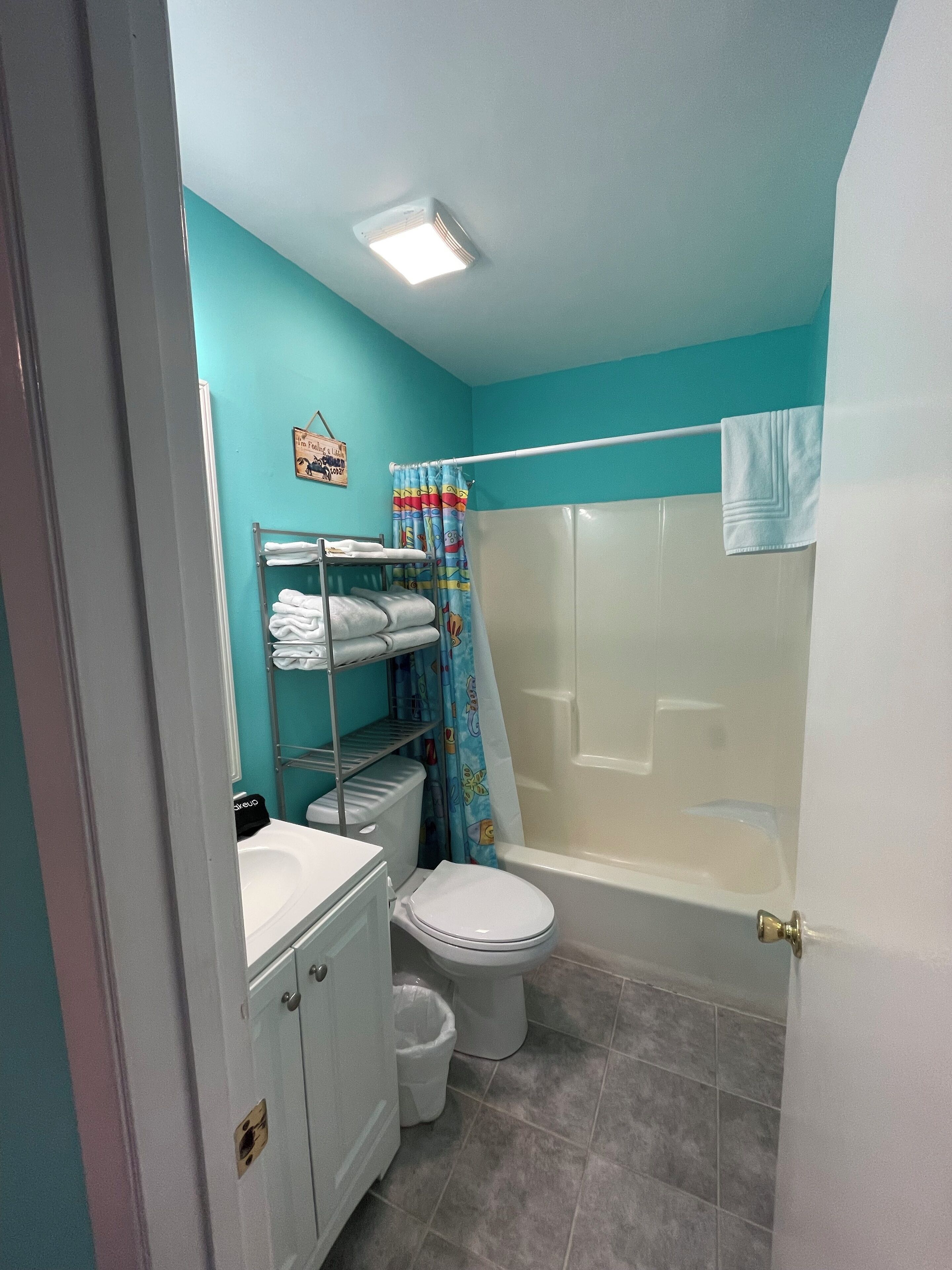 Une salle de bain avec des toilettes, un lavabo et une douche. Il y a des serviettes sur un porte-serviettes et un rideau de douche.