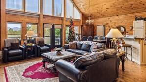 A spacious living room with leather sofas, a coffee table, and a Christmas tree.