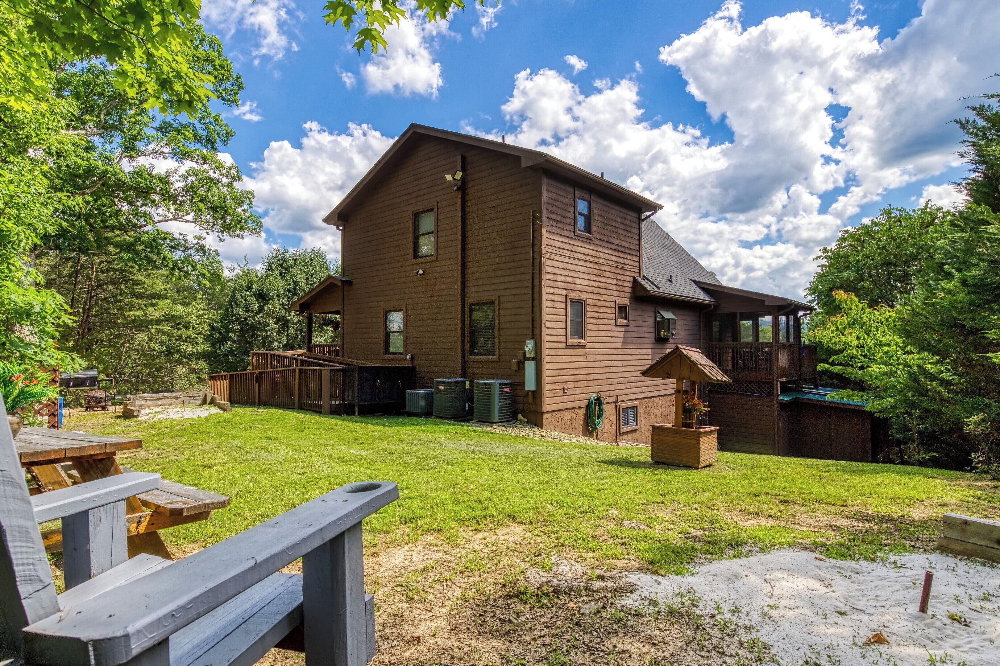 A two-story wooden house with a deck, a covered patio, and a fenced backyard.