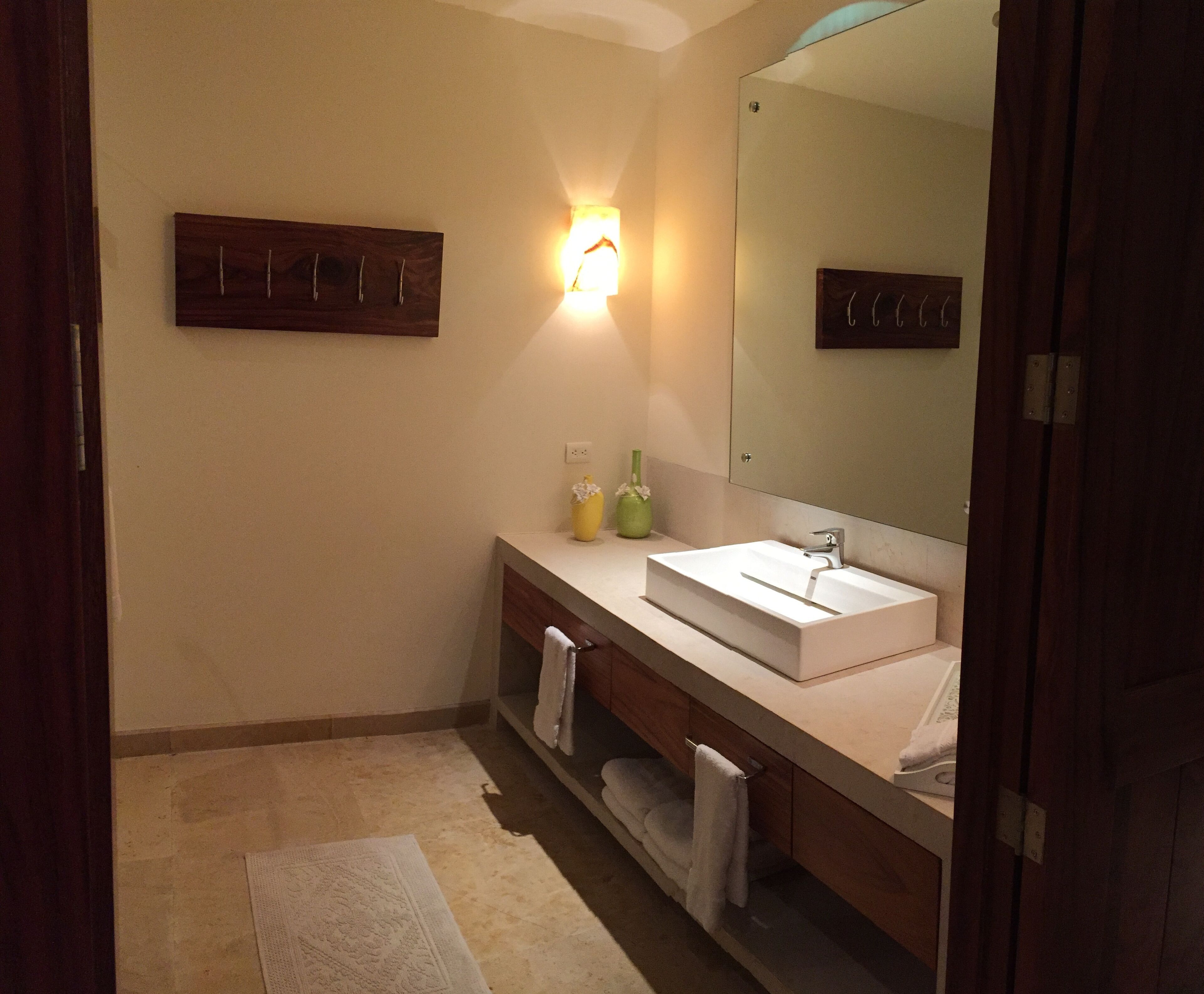 Une salle de bain avec un lavabo blanc, un miroir, un porte-serviettes et un luminaire fixé au mur.