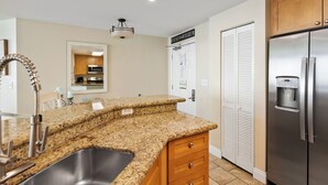 A kitchen with granite countertops, stainless steel appliances, and wooden cabinets. - Aqua 2102 Luxury Gulf Front Escape, Beach Chairs, Walk to Pier Park (Panama City Beach)