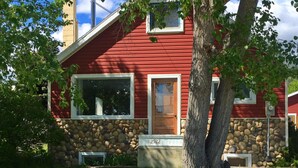 A red house with a stone foundation, a front door, and a mailbox. - The Cozy Red Cabin  (Bellevue)