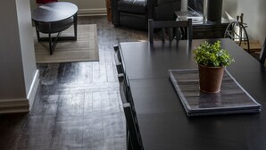 A modern living room with a dark wooden dining table, a comfortable sofa, and a potted plant on the table. - The Cozy Red Cabin  (Bellevue)