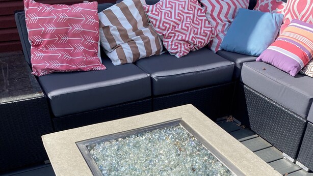 A square table with a glass top, surrounded by a wooden frame, on a deck with grey wooden planks. - The Cozy Red Cabin  (Bellevue)