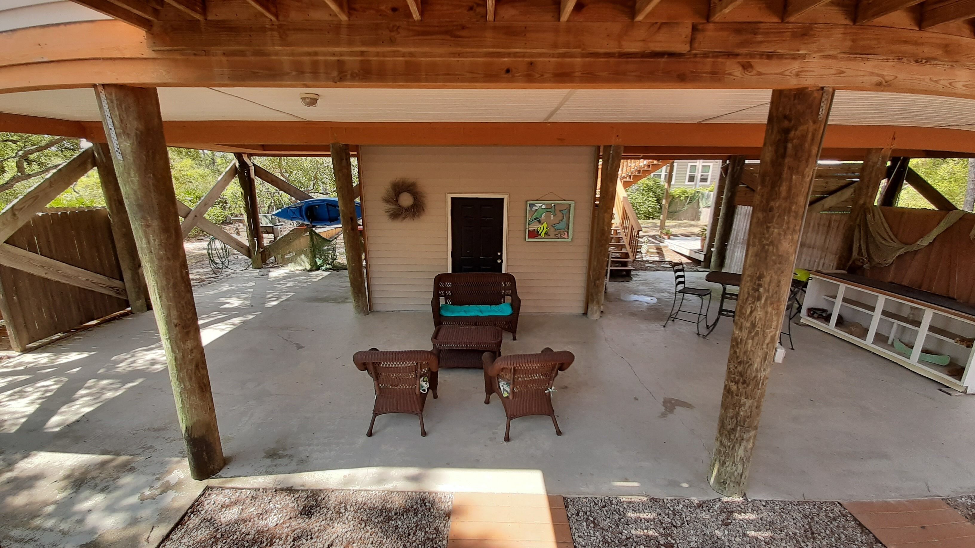 A covered patio area with a seating arrangement and a door leading to a building.