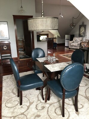 A dining area with a table set for four, surrounded by blue upholstered chairs.