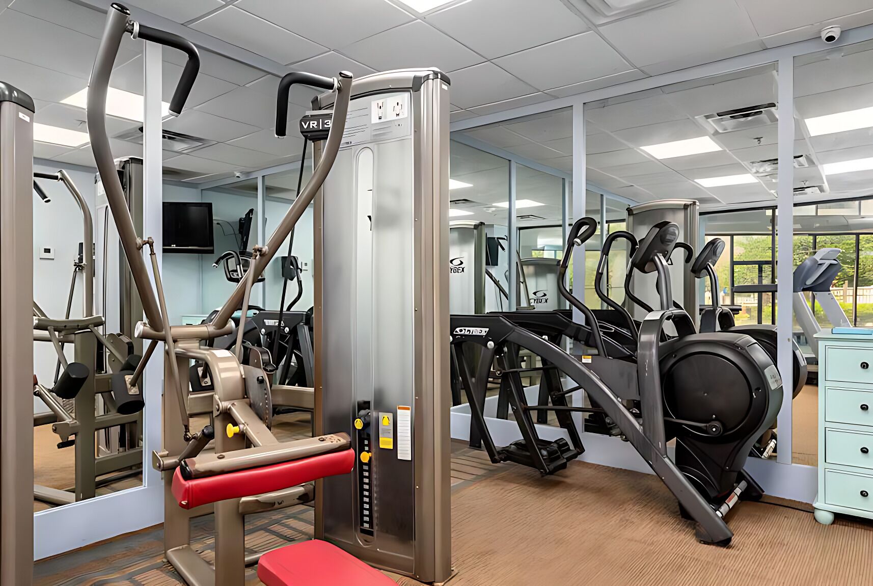 Een sportschool met diverse fitnessapparaten, waaronder loopbanden en gewichten.