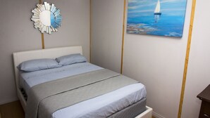 A bedroom with a bed, a wall-mounted mirror, and a painting of a sailboat. - Lakefront Cottage in Manitou Beach - Three Bedroom Cottage, Sleeps 8 (Manitou Beach)
