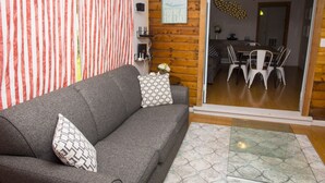 A modern living room with a grey sofa, patterned pillows, a glass coffee table, and a striped curtain. - Lakefront Cottage in Manitou Beach - Three Bedroom Cottage, Sleeps 8 (Manitou Beach)
