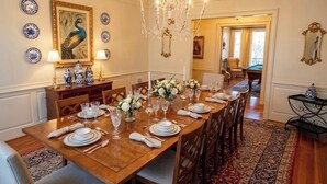 A dining room with a wooden table set for six, surrounded by chairs. A chandelier hangs from the ceiling, and there are decorative plates and a framed painting on the walls. - Large House with Lake Views, pool table and Private Boat Dock (Gainesville)
