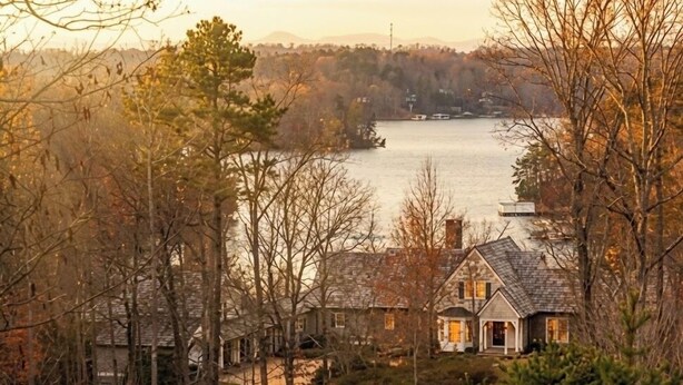 A house with a stone exterior, a visible chimney, and a view of a lake. - Large House with Lake Views, pool table and Private Boat Dock (Gainesville)