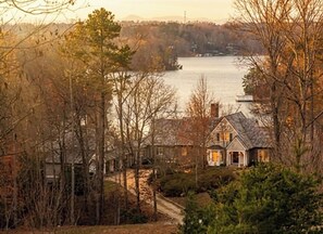 A house with a stone exterior, a visible chimney, and a view of a lake. - Large House with Lake Views, pool table and Private Boat Dock (Gainesville)