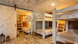 A rustic cabin interior with wooden bunk beds, a sliding barn door, and a herringbone-patterned floor. - Large House with Lake Views, pool table and Private Boat Dock (Gainesville)