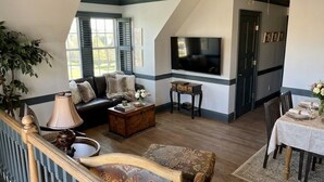 A cozy living room with a sofa, coffee table, and a TV mounted on the wall. - Large House with Lake Views, pool table and Private Boat Dock (Gainesville)
