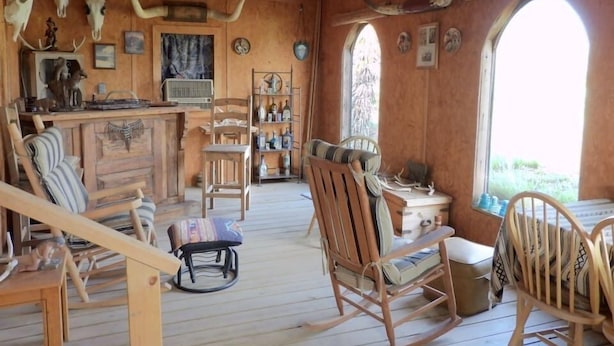 A rustic interior with wooden furniture, a bar area, and a view through a large window. - Corazones Draw Ranch: Spacious Home on 400 acres (Brewster County)