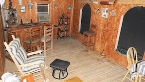 A rustic room with wooden furniture, a fireplace, and wall-mounted decorations. - Corazones Draw Ranch: Spacious Home on 400 acres (Brewster County)