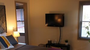 Une chambre d’hôtel moderne dotée d’un grand lit, d’une télévision à écran plat, d’un petit bureau et d’une fenêtre avec des stores.