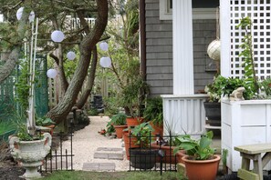 Un giardino con piante in vaso, un recinto bianco e un vialetto.